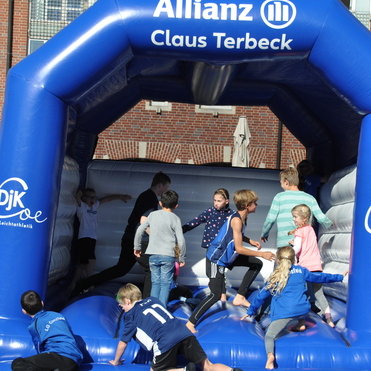 Gruppe von Kindern spielt auf einem blauen H&uuml;pfburg, fr&ouml;hlich und aktiv im Freien.