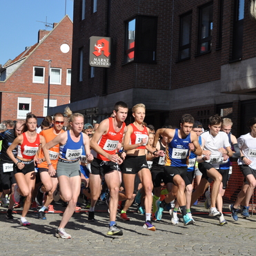 Start eines Laufevents mit Teilnehmern in Sportkleidung an einer urbanen Stra&szlig;e. Zuschauer applaudieren am Rand.