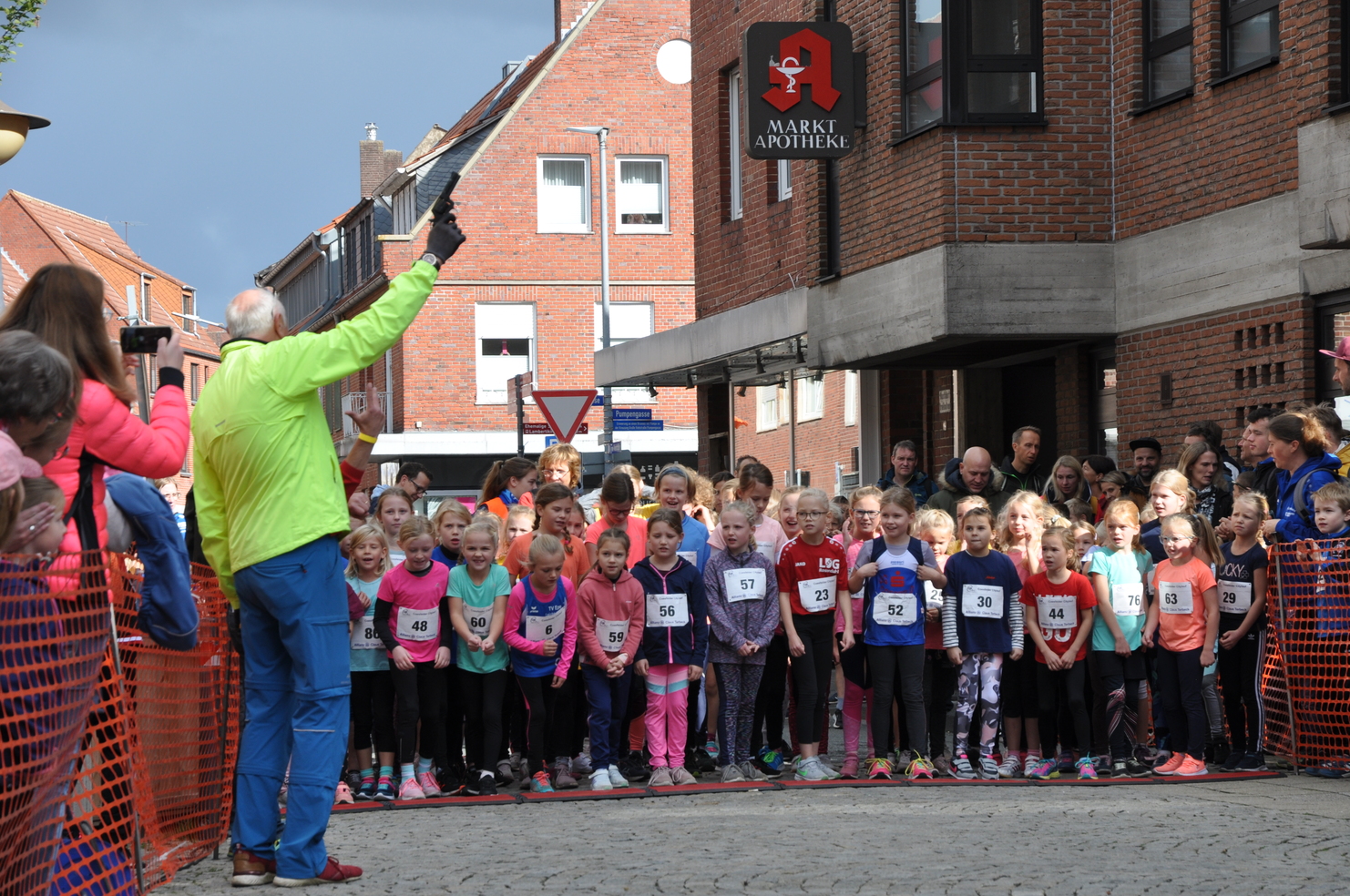 Gruppierung von Mädchen in Sportkleidung, die am Start eines Laufwettbewerbs an einer Straße warten.
