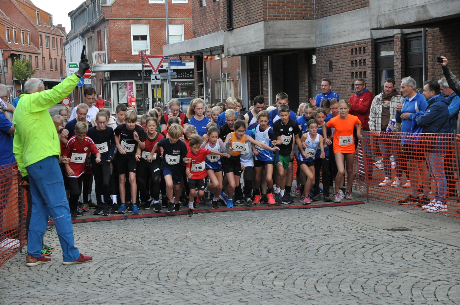 Start einer Kinder-Laufveranstaltung mit jungen Teilnehmern an einer gepflasterten Straße und Zuschauern im Hintergrund.