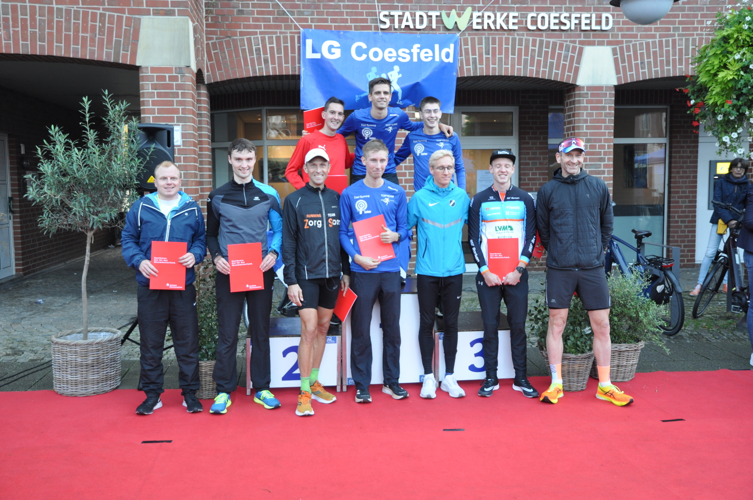Gruppenshot von Sportlern mit Urkunden auf einem roten Teppich vor einem Gebäude der Stadtwerke Coesfeld.