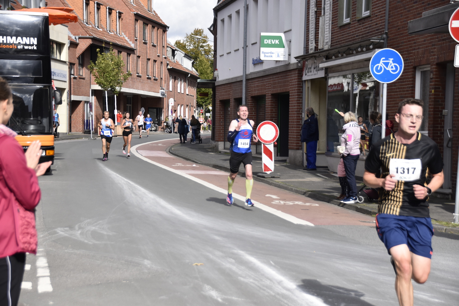 Läufer in Wettkampfkleidung beim Marathon auf einer Stadtstraße, umgeben von Zuschauern und Straßenverkehr.