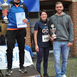 Drei Läufer auf dem Siegertreppchen halten Pokale und Urkunden nach einem Wettkampf in Coesfeld.