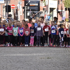 Gruppe von Mädchen in Sportkleidung steht an einer Startlinie für ein Rennen in einer Stadtstraße.