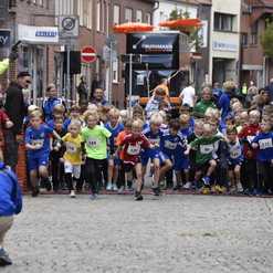 Startschuss für einen Kinderlauf mit vielen jungen Teilnehmern in bunten Trikots auf einer Straßensportveranstaltung.