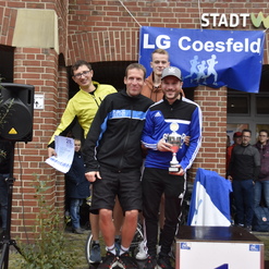Fünf Männer feiern auf dem Siegertreppchen mit Pokal und Medaillen, im Hintergrund ein Banner der LG Coesfeld.