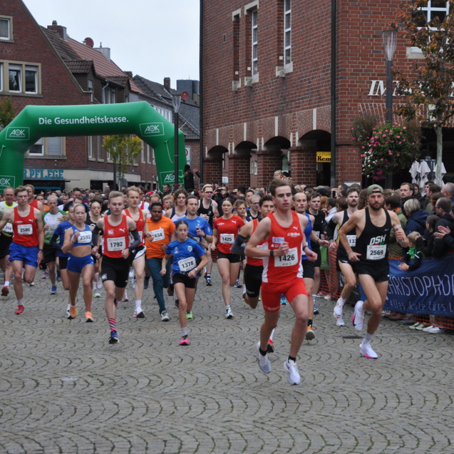 Startschuss eines Laufwettbewerbs mit vielen Teilnehmern auf einer gepflasterten Straße, Umrandung aus Zuschauern.