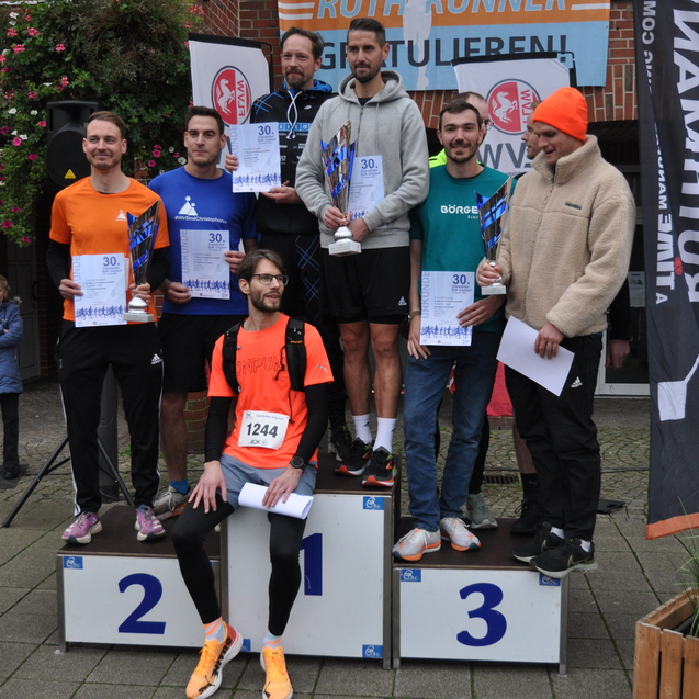 Sieben M&auml;nner stehen auf einem Siegertreppchen und halten Urkunden und Pokale nach einem Laufwettbewerb.