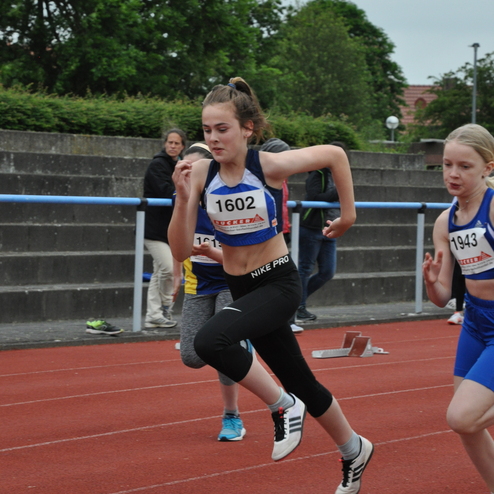 Zwei Athletinnen sprinten auf einer roten Laufbahn, eine trägt die Startnummer 1602, die andere 1943.