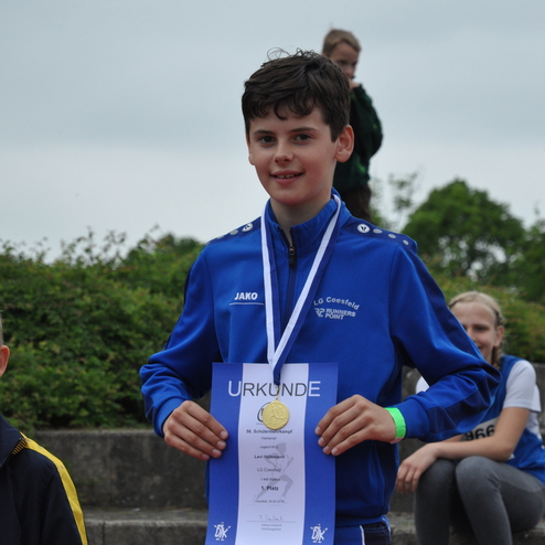 Junge in blauer Sportjacke hält Urkunde und Medaille für den 1. Platz beim 56. Schülerkampf in Coesfeld.