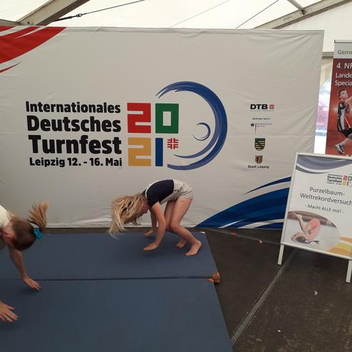 Zwei Kinder führen einen Purzelbaum auf einer blauen Turnmatte während des Deutschen Turnfests in Leipzig durch.
