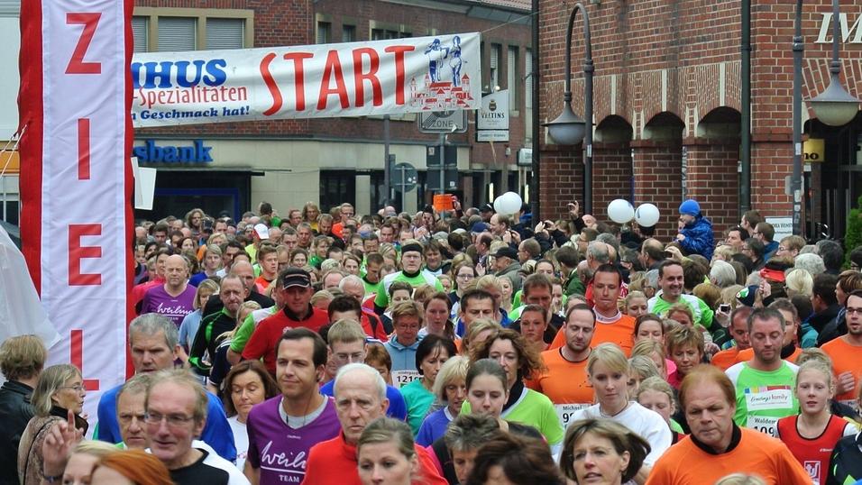 Startschuss eines Lauf-Events mit vielen Teilnehmern in bunten T-Shirts auf einer belebten Straße.