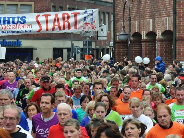 Startschuss eines Lauf-Events mit vielen Teilnehmern in bunten T-Shirts auf einer belebten Straße.