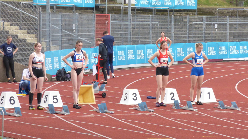 Fünf Leichtathletinnen stehen an der Startlinie auf einer roten Bahn, bereit für den Wettkampf bei den Ruhr Games.
