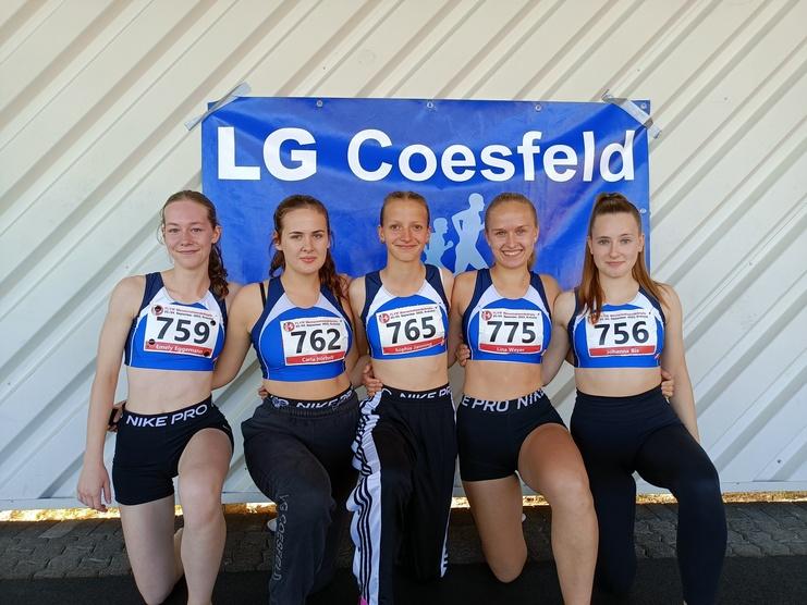 Fünf junge Athletinnen posieren vor einem Banner der LG Coesfeld, gekleidet in Sportoutfits mit Startnummern.
