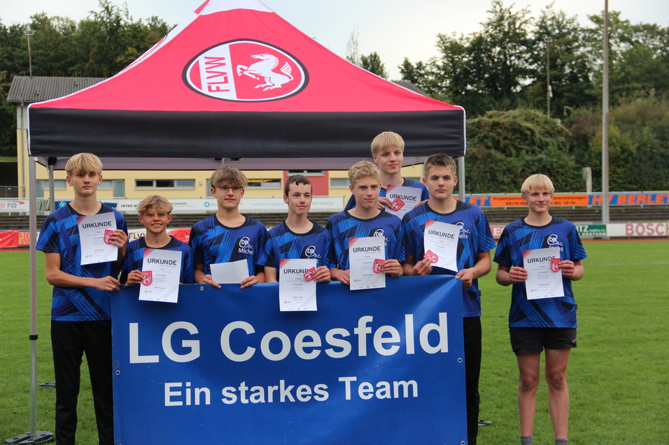 Gruppenbild von acht Jugendlichen in blauen Sportshirts, die Urkunden vor einem Banner der LG Coesfeld halten.