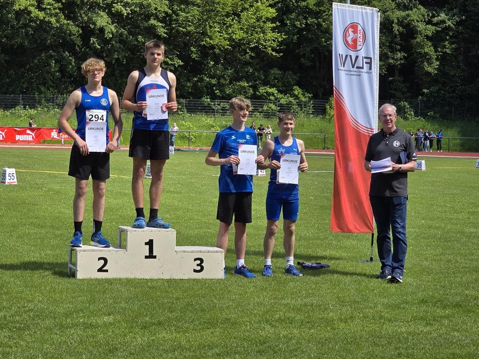 Vier Jugendliche stehen auf dem Treppchen bei einer Leichtathletikveranstaltung und halten Urkunden in den Händen.