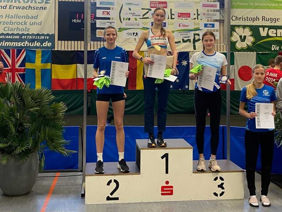 Vier Athletinnen stehen auf dem Siegertreppchen mit Urkunden beim 20. Sparkassen Hochsprungmeeting in einer Sporthalle.