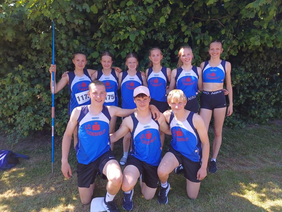 Gruppenfoto von zehn Jugendlichen in Sportkleidung der LG Coesfeld, stehen vor einer grünen Hecke.