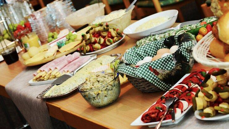 Buffet mit verschiedenen Speisen: Wurst, K&auml;se, frisches Gem&uuml;se, Eier und Salate auf einem Tisch angerichtet.