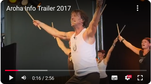 Eine Gruppe von Tänzern mit Stöcken führt eine dynamische Choreografie auf einer Bühne vor Publikum auf.