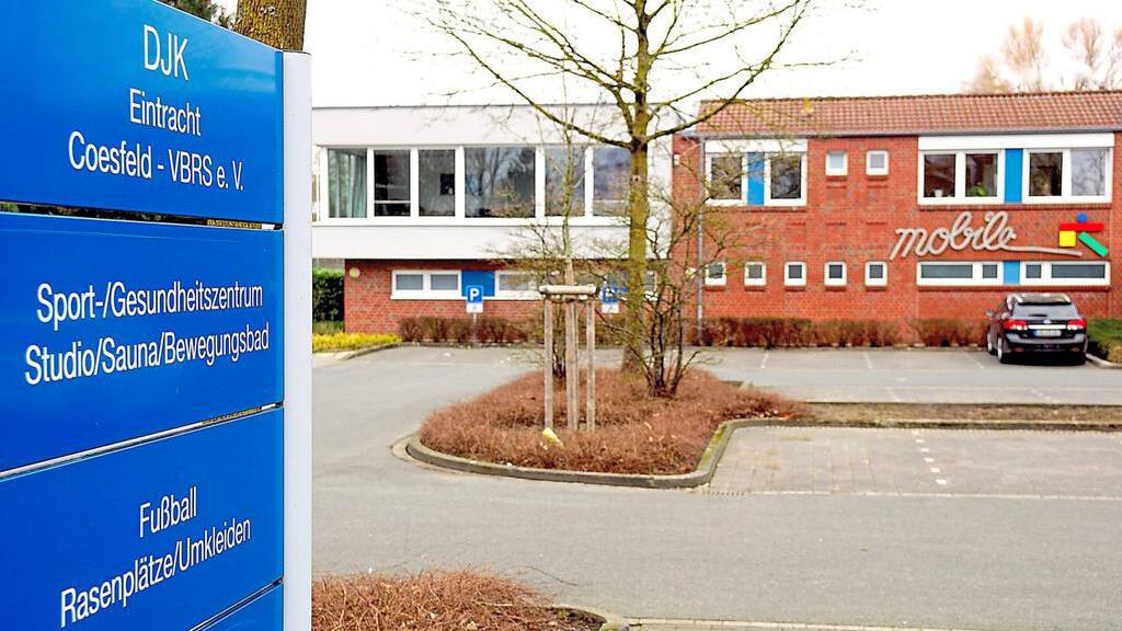 DJK Eintracht Coesfeld: blaues Hinweisschild vor einem Sport- und Gesundheitszentrum mit angrenzendem Parkplatz.
