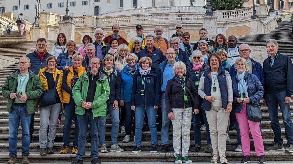 Gruppe von 39 Personen steht auf den spanischen Treppen in Rom, mit zwei Kirchen im Hintergrund.