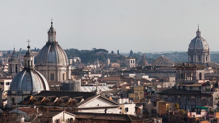 Panoramablick auf die Dächer Roms mit mehreren Kuppeln und Gebäuden im Hintergrund an einem klaren Tag.