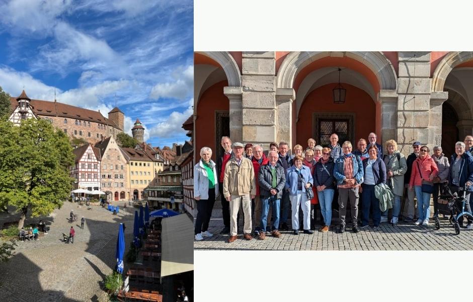 Gruppe von 23 Personen steht lächelnd vor historischer Architektur mit Säulen und Fenstern. Heller Himmel im Hintergrund.